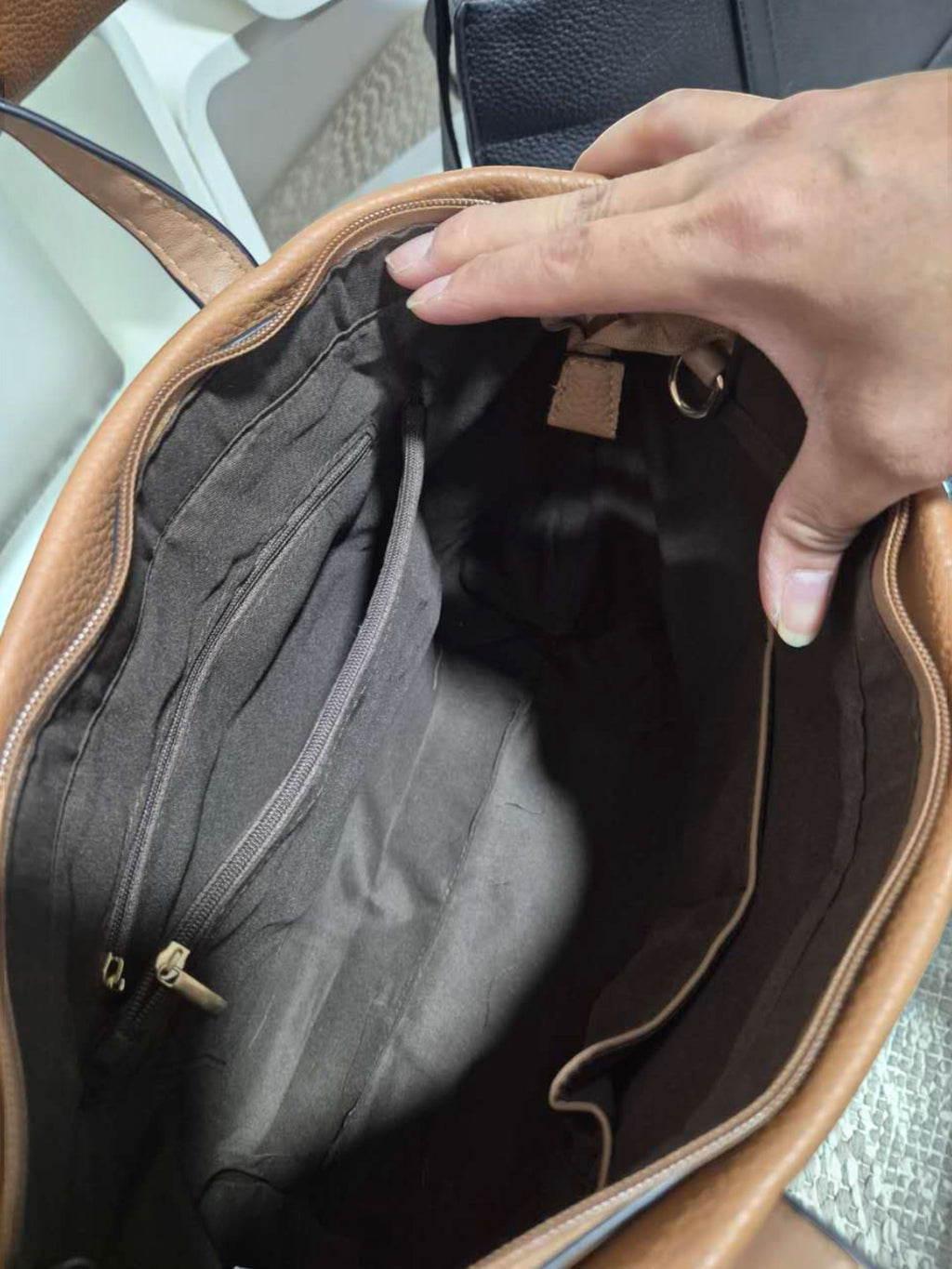 Interior view of a BROCK MIA LAROUGE tan shoulder bag showing dark fabric lining, zippered pocket, and compartments.