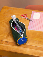 BROCK Mia tricolor pencil case in sage green, blue, and yellow on a wooden desk with school supplies.