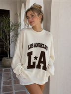 BROCK MISS CHARM beige cotton knit sweater with Los Angeles LA graphic lettering worn by a woman