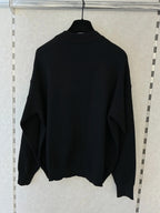 BROCK MISS CHARM black cotton knit sweater with a round neck and long sleeves hanging on a hanger