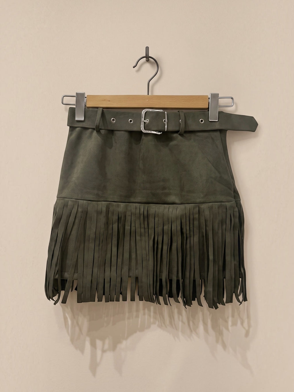 BROCK MOOYA olive green faux suede mini skirt with fringe hem and matching belt with silver buckle on a hanger