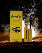 BROCK NATURALASH volumizing eyelash serum in a yellow bottle and box with a brush applicator against a dark background