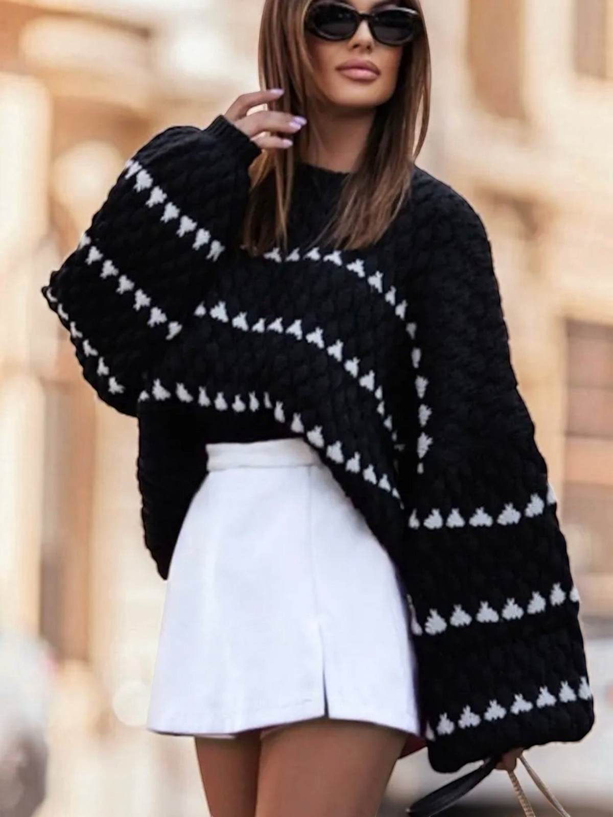 BROCK oversize black knit sweater with white triangular striped patterns worn by a woman with sunglasses