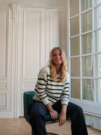 Femme souriante portant un pull marinière en coton BROCK avec col rond, bordures ondulées et boutons aux épaules.