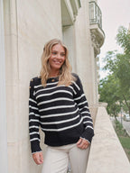 Femme souriante portant un pull marinière BROCK en coton noir et blanc avec boutons dorés sur les épaules