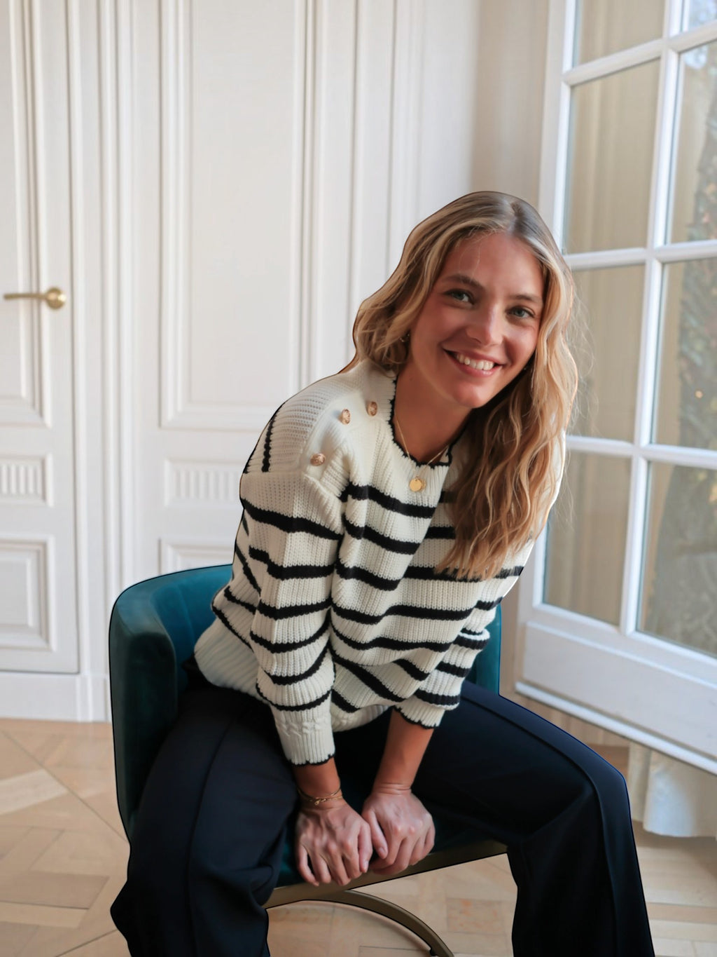 Femme souriante portant un pull marinière BROCK en coton blanc et noir avec boutons dorés aux épaules