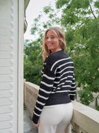 Femme souriante portant un pull marinière BROCK en maille de coton noir et blanc avec boutons dorés sur l'épaule