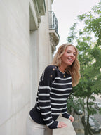 Femme portant un pull marinière BROCK en coton noir et blanc avec boutons dorés sur l'épaule et bords ondulés