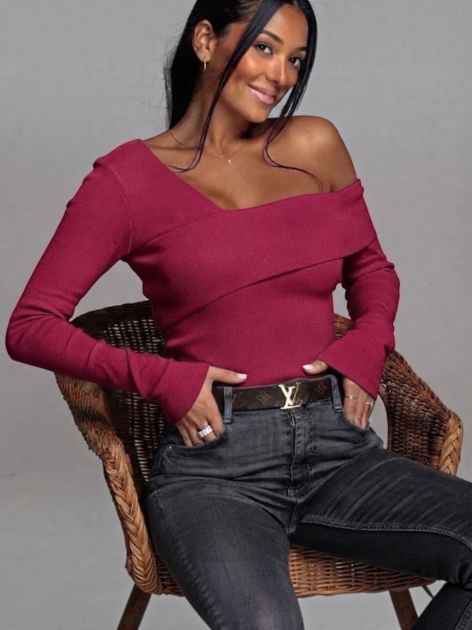 BROCK long sleeve red bardot top with a crossover neckline worn by a woman sitting in a wicker chair