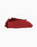 A rich red matte lipstick swatch from BROCK, showing intense pigmentation and a smooth, creamy texture.