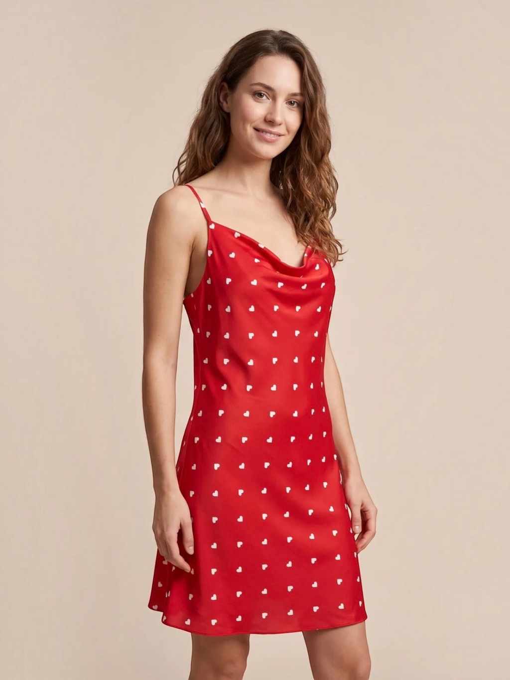 Model wearing a red satin nightie with white heart pattern, cowl neckline, and adjustable straps by BROCK