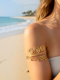 BROCK Rosa gold stainless steel spiral armlet worn on a woman's arm at a sunny beach