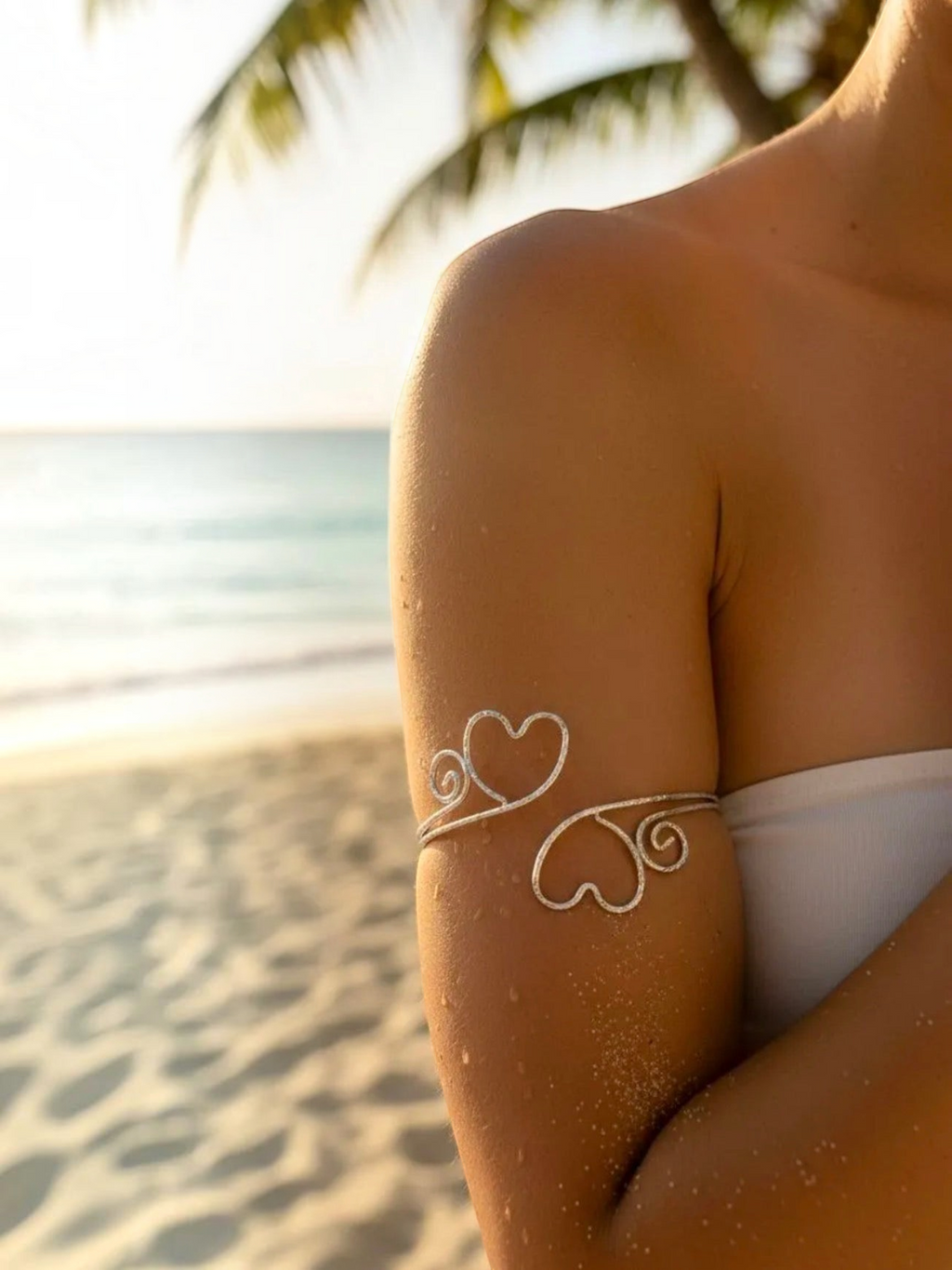 BROCK Rosa stainless steel armlet featuring a delicate heart design worn on the upper arm at a sunny beach