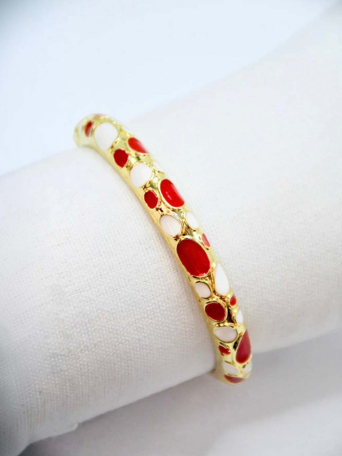 BROCK ROSA Thai-inspired brass bangle bracelet featuring a gold finish with red and white enamel pebble patterns.
