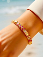 BROCK ROSA Thai-inspired brass bangle bracelet with pink and white floral enamel details worn on a wrist.