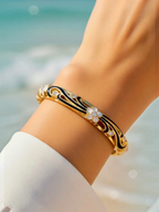 BROCK ROSA Thai-inspired gold brass bangle bracelet with black enamel, white floral accents, and sparkling crystals.