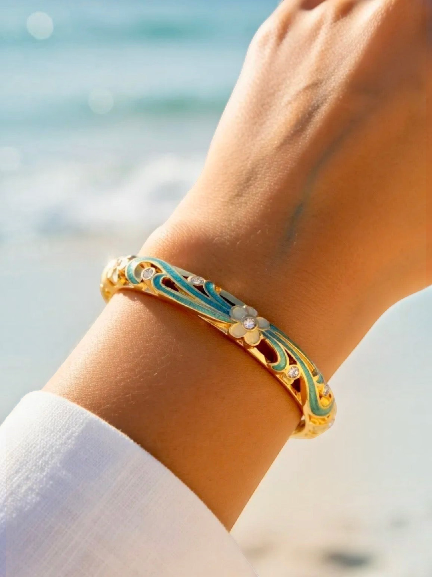 BROCK ROSA Thai-inspired brass bangle bracelet with turquoise enamel floral details and crystals on a wrist