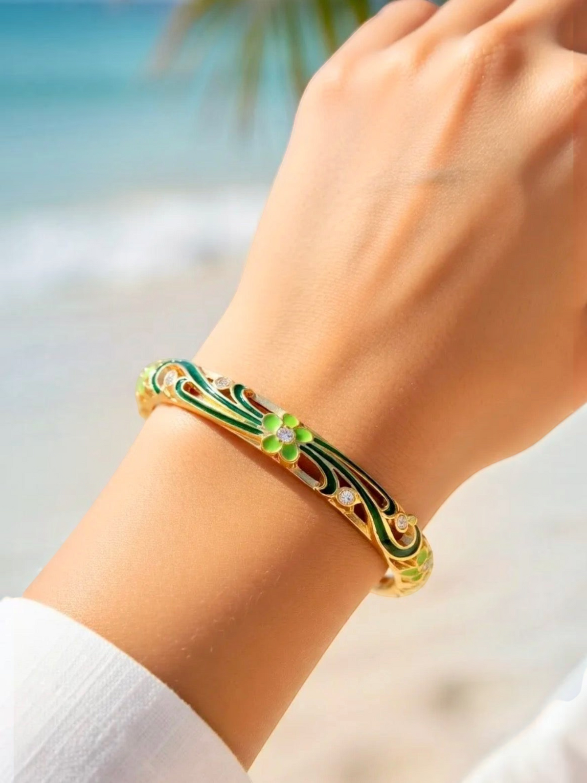 BROCK ROSA Thai-inspired brass bangle featuring green floral enamel detailing and sparkling crystal accents on wrist
