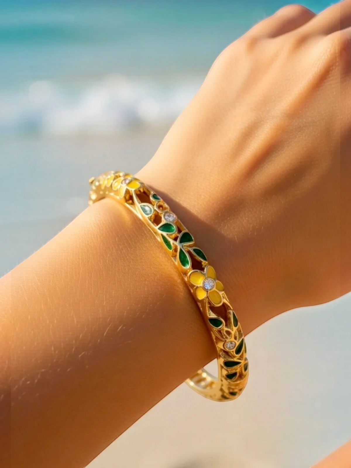BROCK ROSA Thai-inspired brass bangle bracelet with yellow floral enamel and crystal accents on a woman's wrist