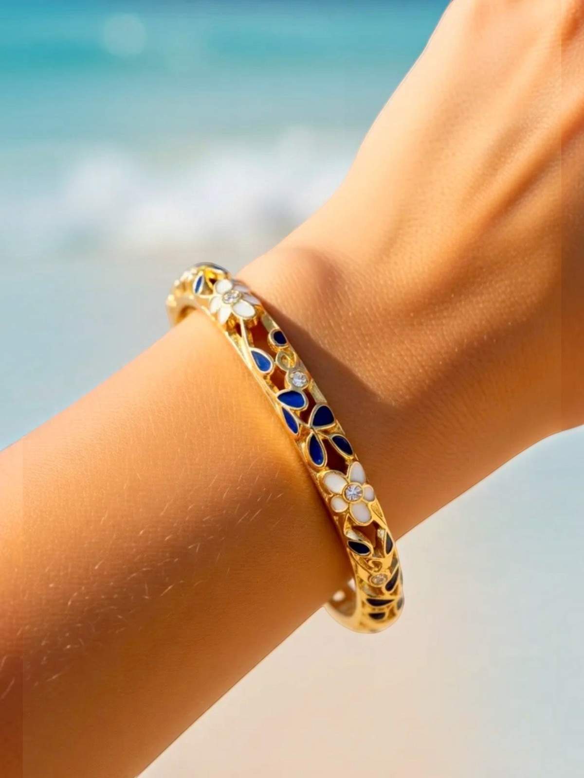 BROCK ROSA Thai-inspired brass bangle bracelet with blue and white floral enamel details on a woman's wrist