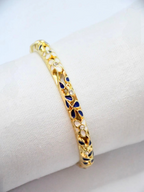 BROCK ROSA Thai-inspired gold brass bangle bracelet featuring white and blue floral enamel details with crystal accents