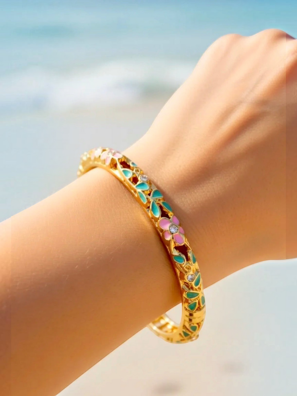 BROCK ROSA Thai-inspired gold brass bangle bracelet with colorful floral enamel and crystal accents on a wrist.