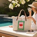 Grand sac cabas BROCK en toile beige avec anses en cuir, motif lèvres Bisou et finitions frangées au bord de piscine.