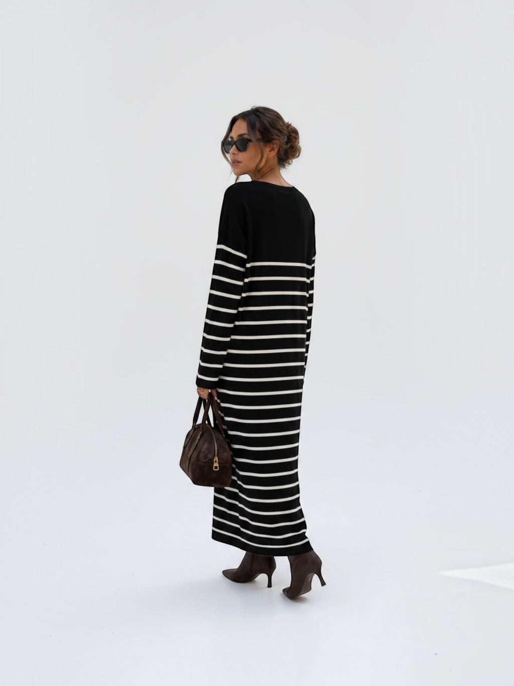 Model wearing a BROCK long-sleeved striped maxi dress with a V-neck, styled with brown boots and a handbag.