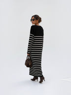 Model wearing a BROCK long-sleeved striped maxi dress with a V-neck, styled with brown boots and a handbag.