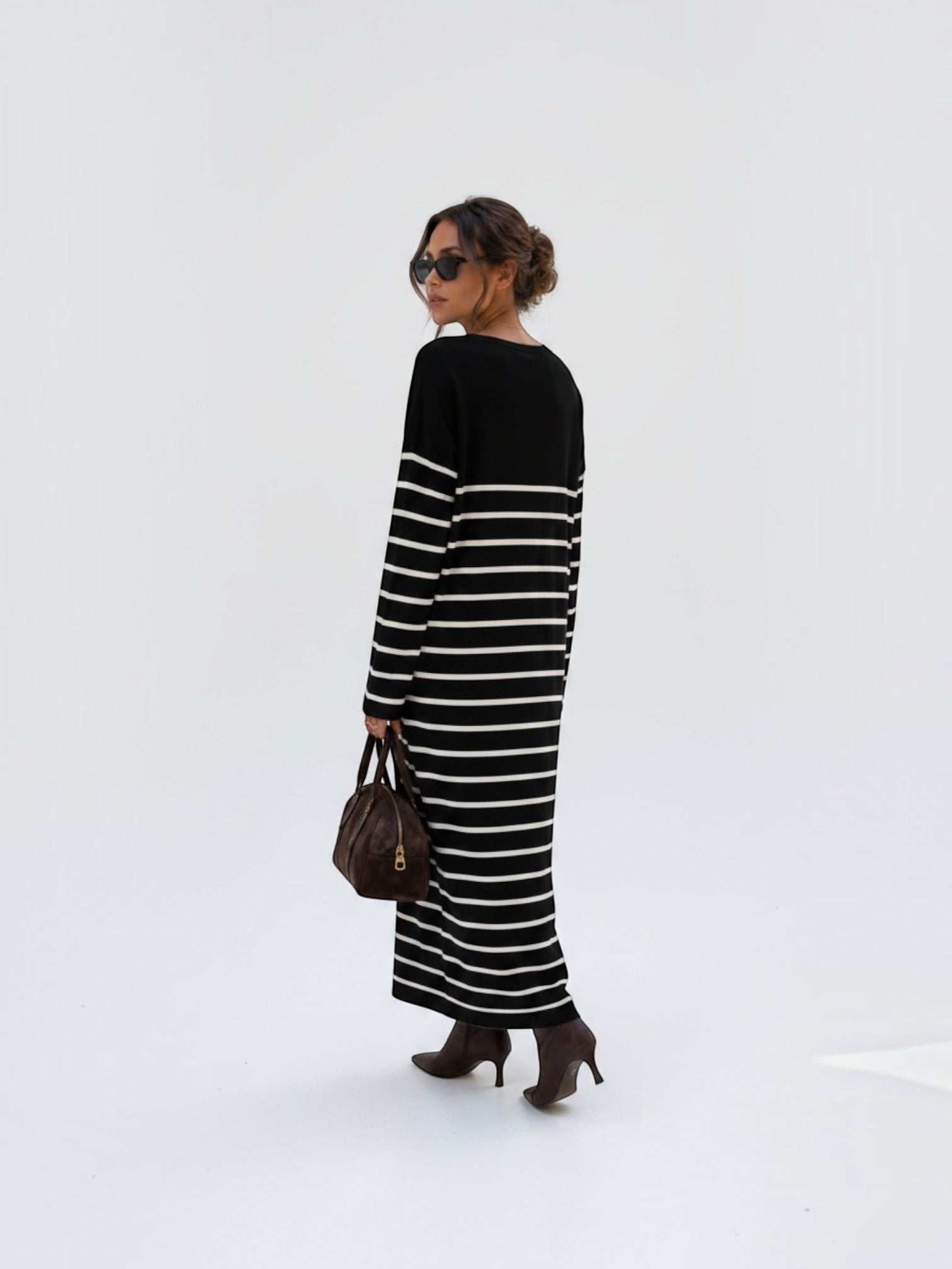Model wearing a BROCK long-sleeved striped maxi dress with a V-neck, styled with brown boots and a handbag.