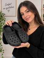 Woman holding black BROCK SUNSEA breathable EVA clogs with perforated design and non-slip soles