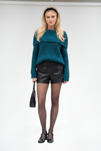 Model wearing a BROCK teal blue textured bardot sweater with black leather shorts, tights, and a black headband.