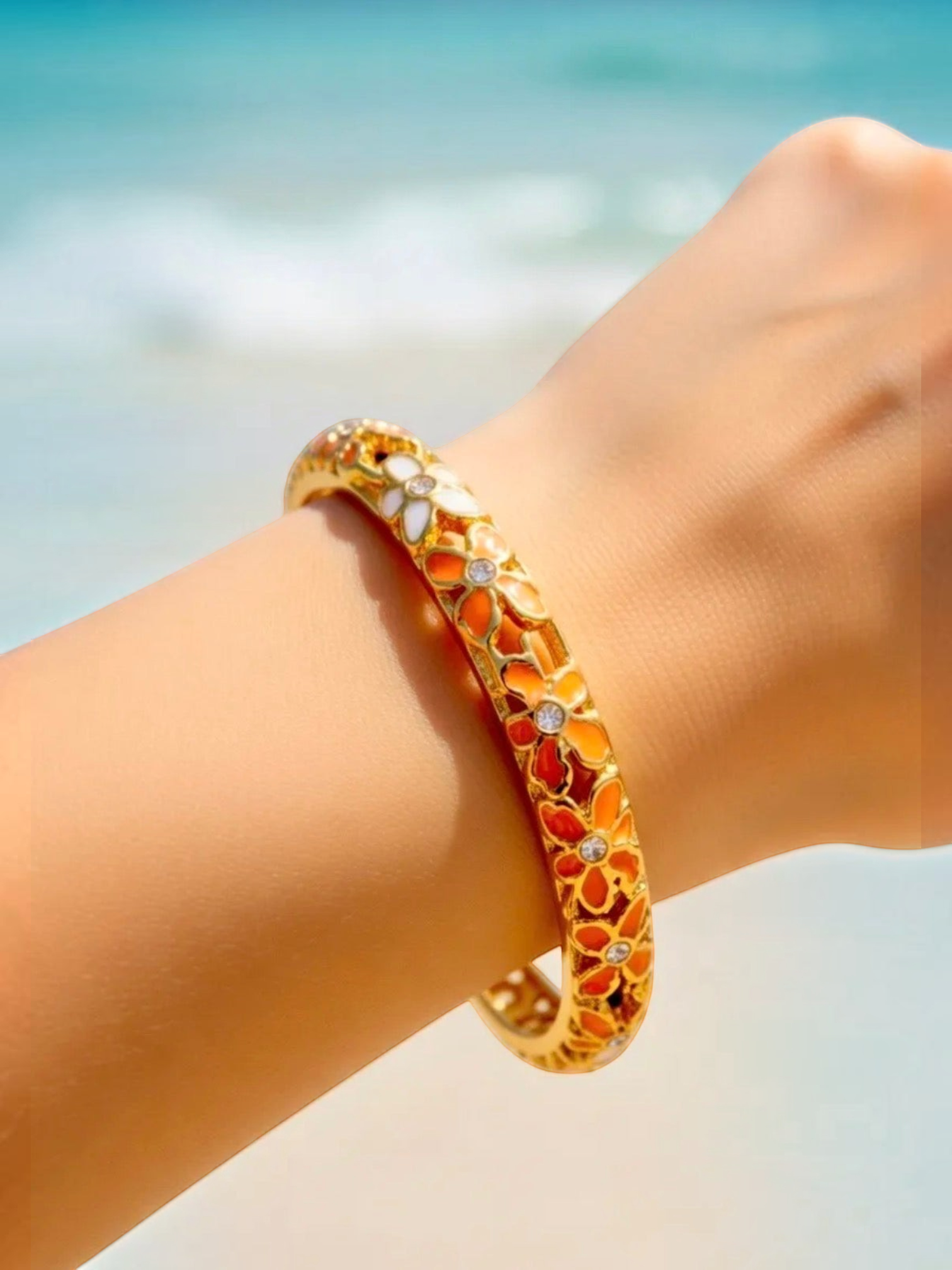 BROCK Thai-inspired brass bangle bracelet with orange and white floral enamel details worn on a wrist