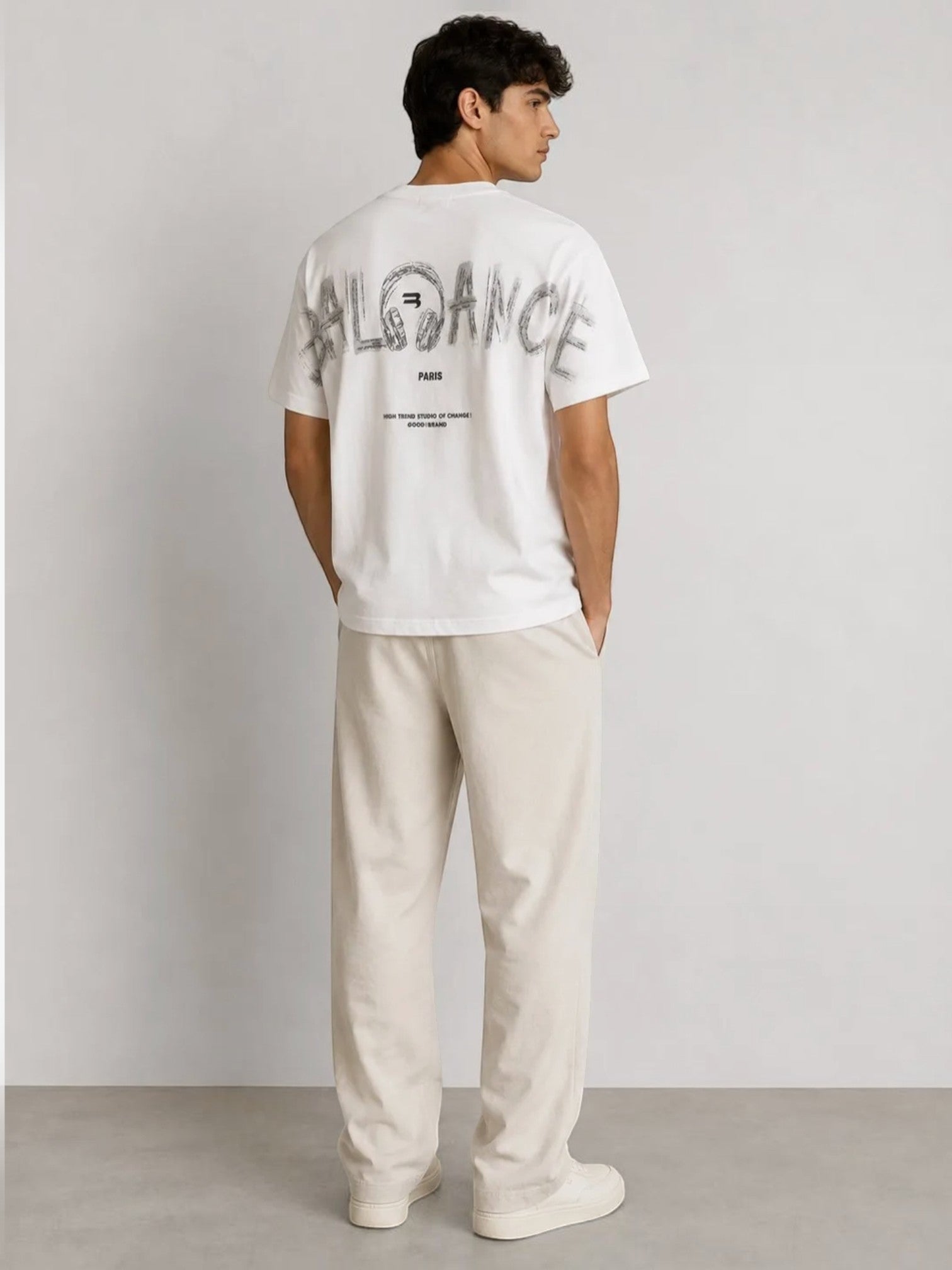 Man wearing a white BROCK cotton t-shirt with a large black typographic graphic print on the back, view from behind.