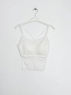 BROCK white lace crop top tank with built-in cups and delicate spaghetti straps hanging on a white hanger