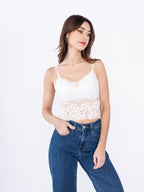 Model wearing a white BROCK lace crop top with built-in cups and thin straps, paired with blue denim jeans.