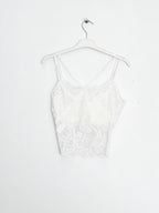 BROCK white lace crop top tank with built-in cups and delicate spaghetti straps hanging on a white hanger