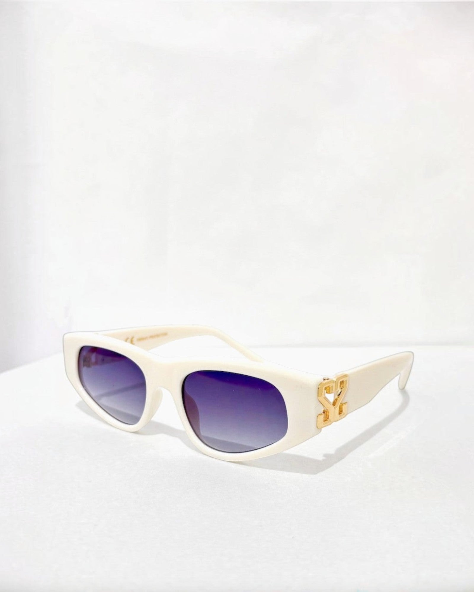 Lunettes de soleil ÉLINE L'ATELIER blanches avec logo doré, monture épaisse et verres dégradés violets.