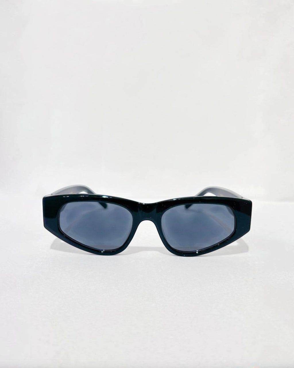 Lunettes de soleil ÉLINE L'ATELIER noires, monture épaisse et verres gris fumé, design géométrique audacieux.