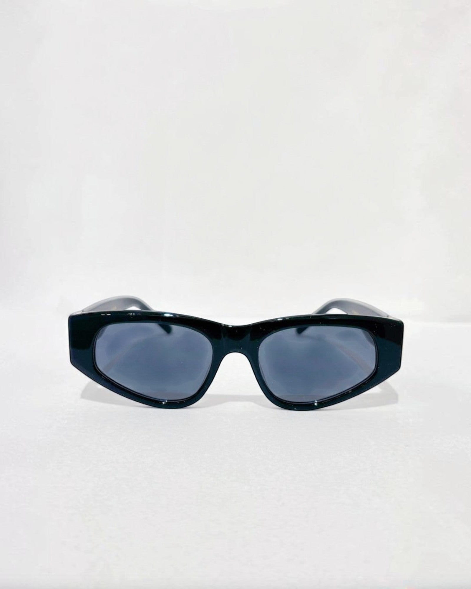 Lunettes de soleil ÉLINE L'ATELIER noires, monture épaisse et verres gris fumé, design géométrique audacieux.