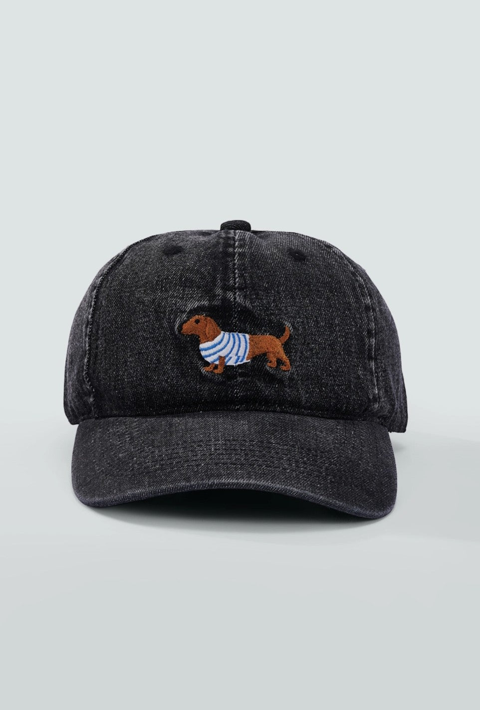 Casquette en coton noir avec broderie d'un chien dachshund portant un pull rayé bleu et blanc.