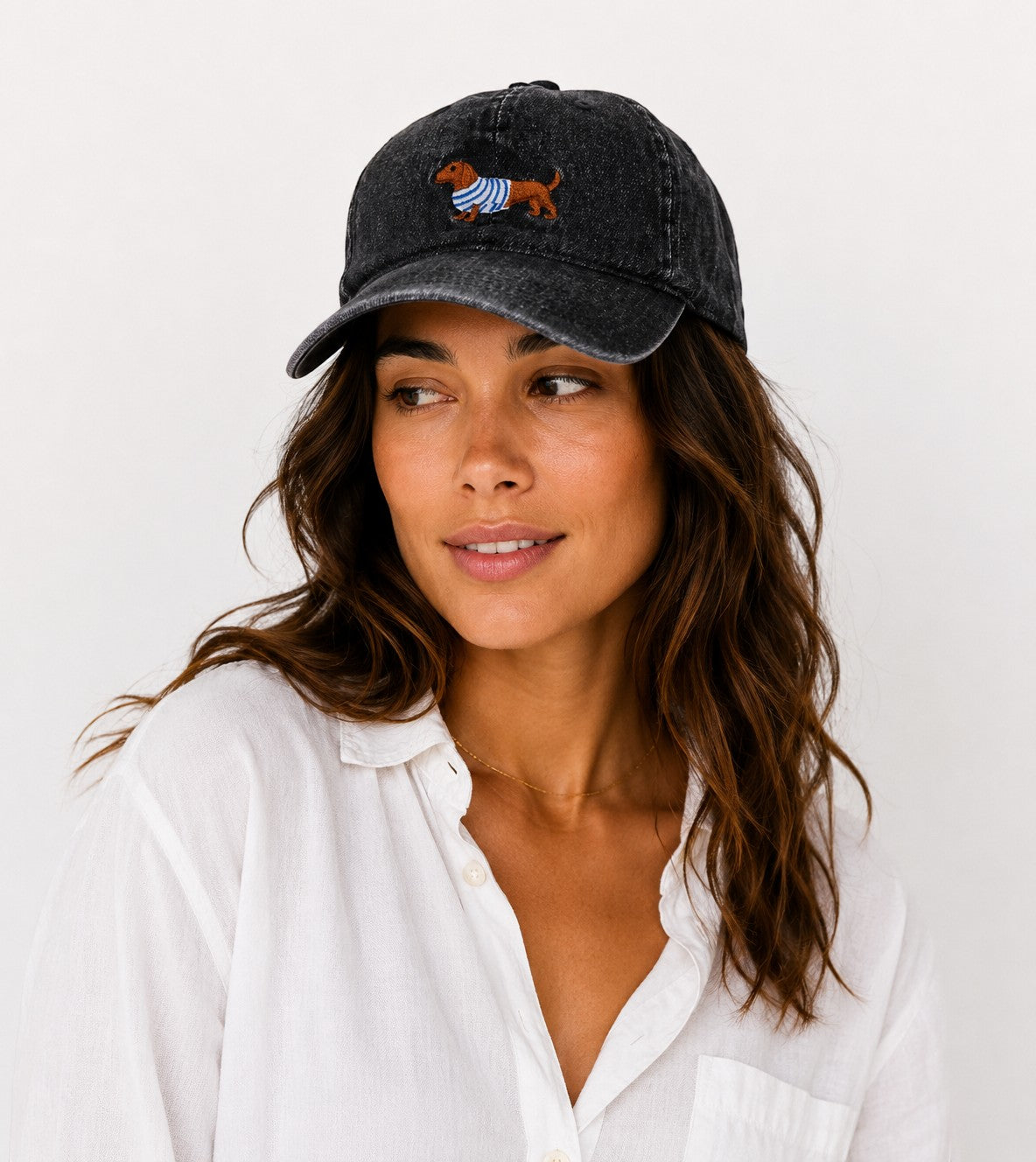 Casquette en coton noir  avec broderie chien dachshund portant un pull rayé bleu et blanc.