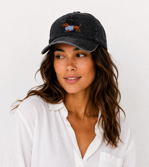 Casquette en coton noir  avec broderie chien dachshund portant un pull rayé bleu et blanc.