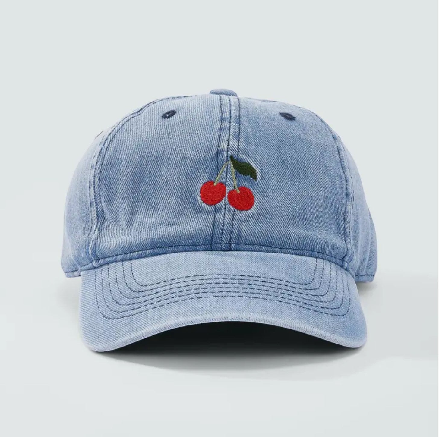 Casquette en jean bleu clair avec broderie cerises rouges et vertes à l'avant. Coton.