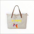 Grand sac cabas de plage  en toile naturelle avec anses en cuir, bords effilochés et motif St. Tropez Party.