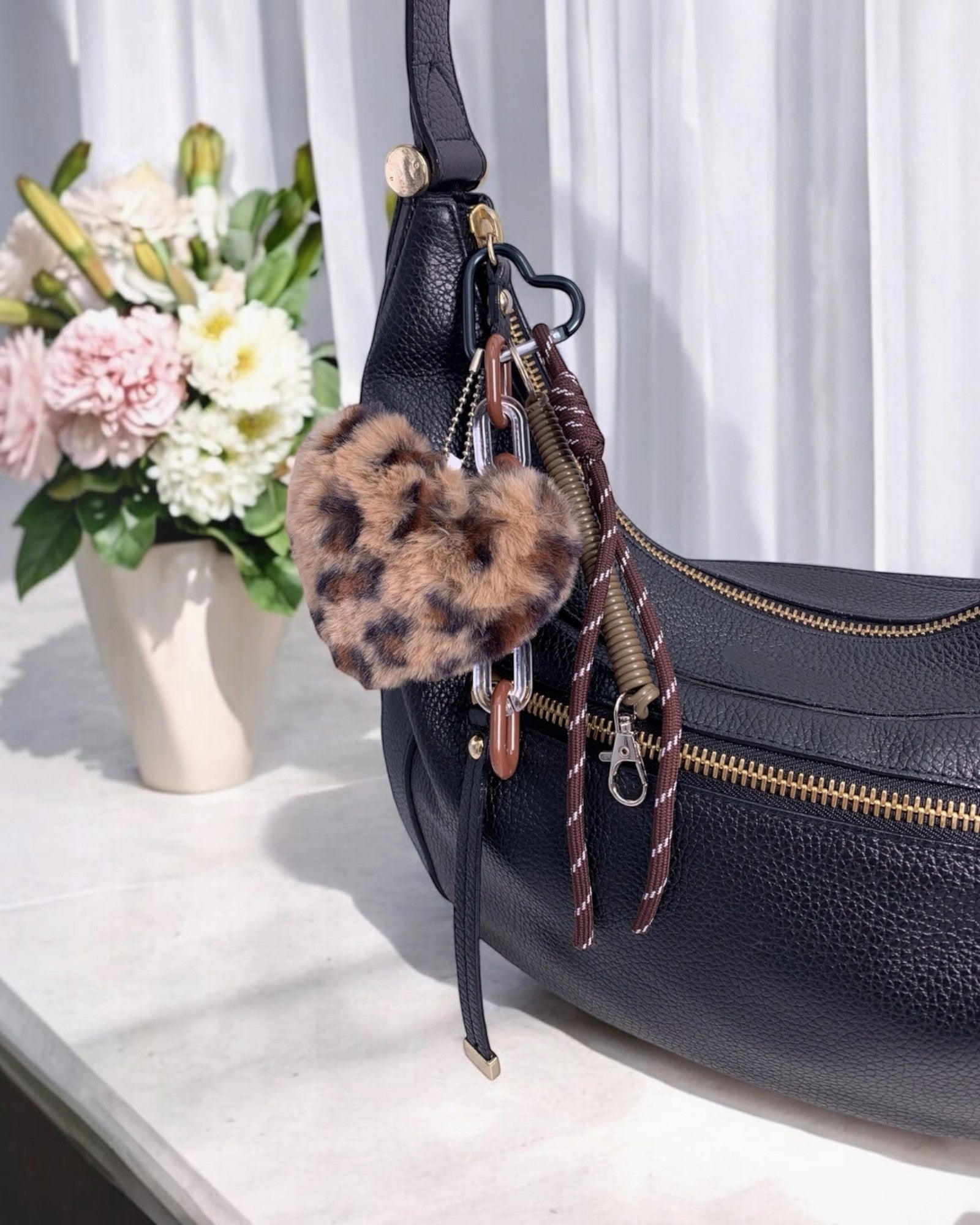 Porte-clés en fausse fourrure en forme de cœur avec imprimé léopard marron et noir.