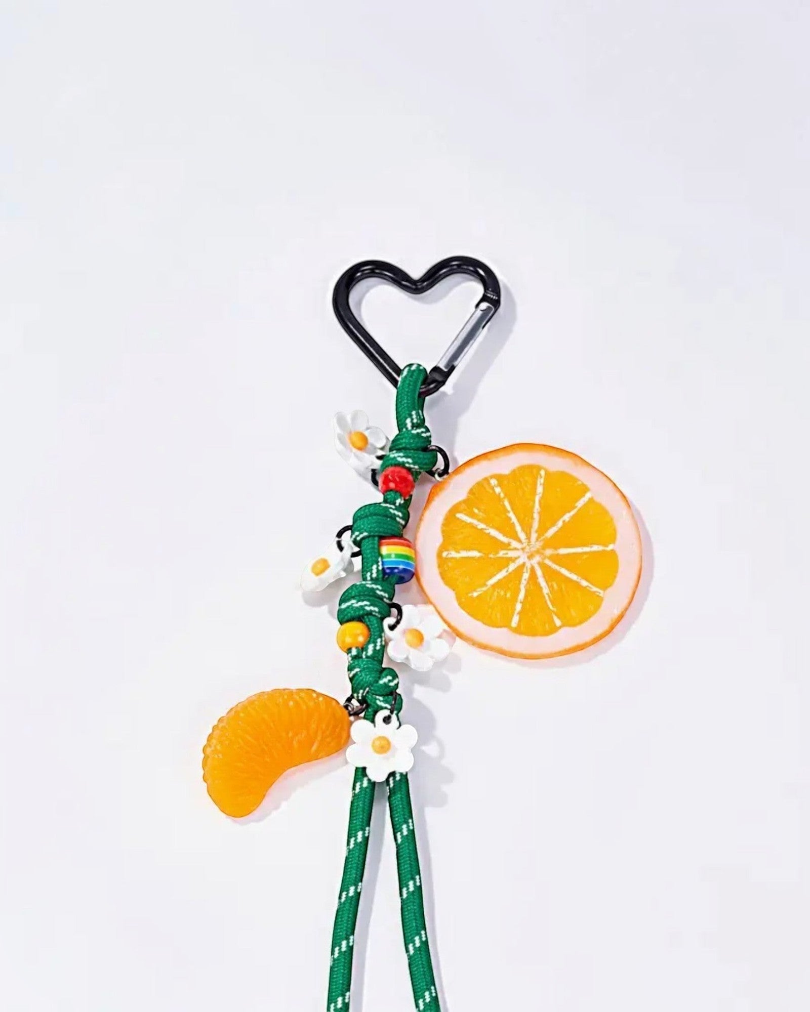 Porte-clés fantaisie avec breloques orange, mandarine, fleurs blanches et arc-en-ciel sur cordon vert.