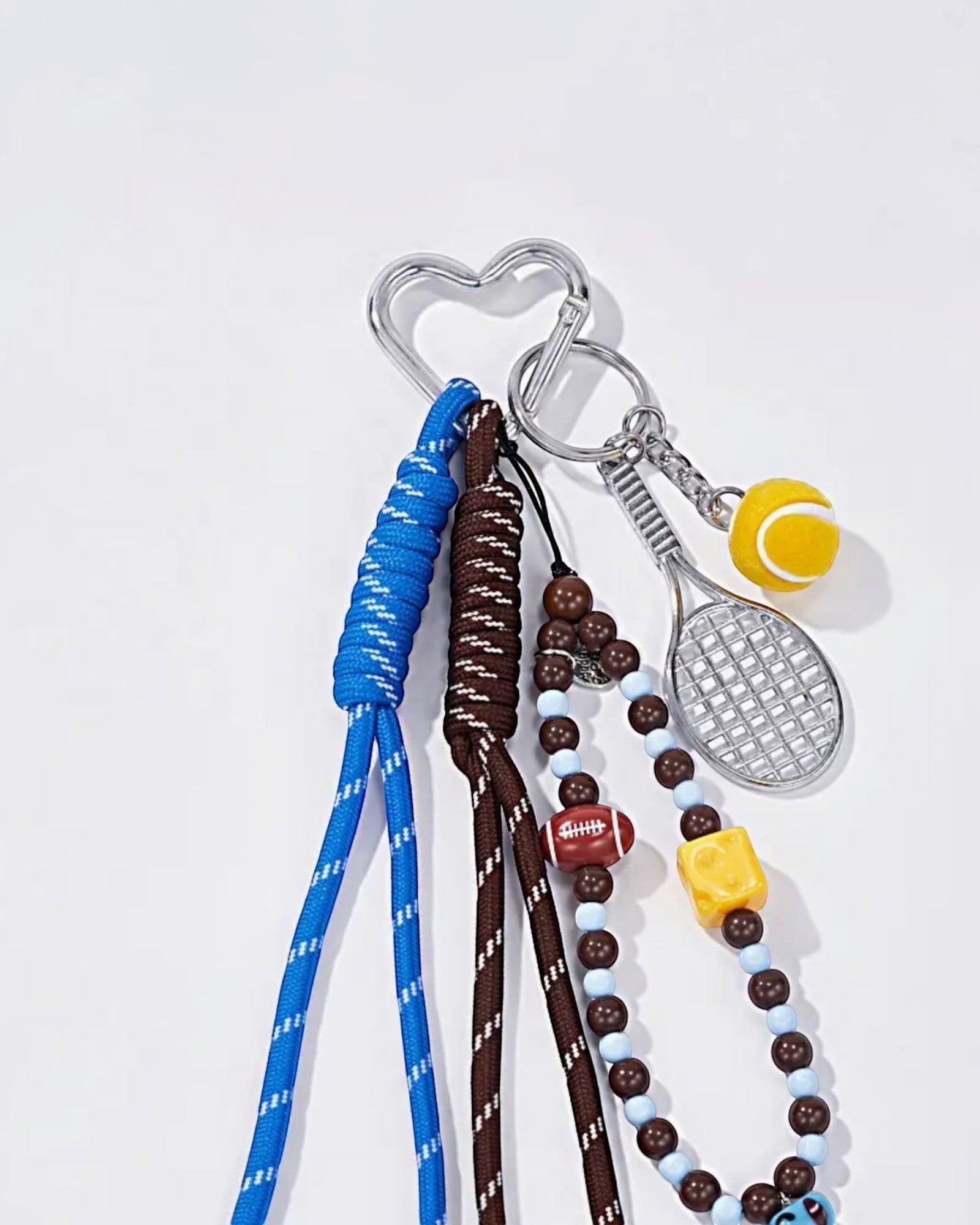 Porte-clés fantaisie  avec breloques sportives : raquette, balle de tennis, ballon de football, perles bleues, marron et fromage.