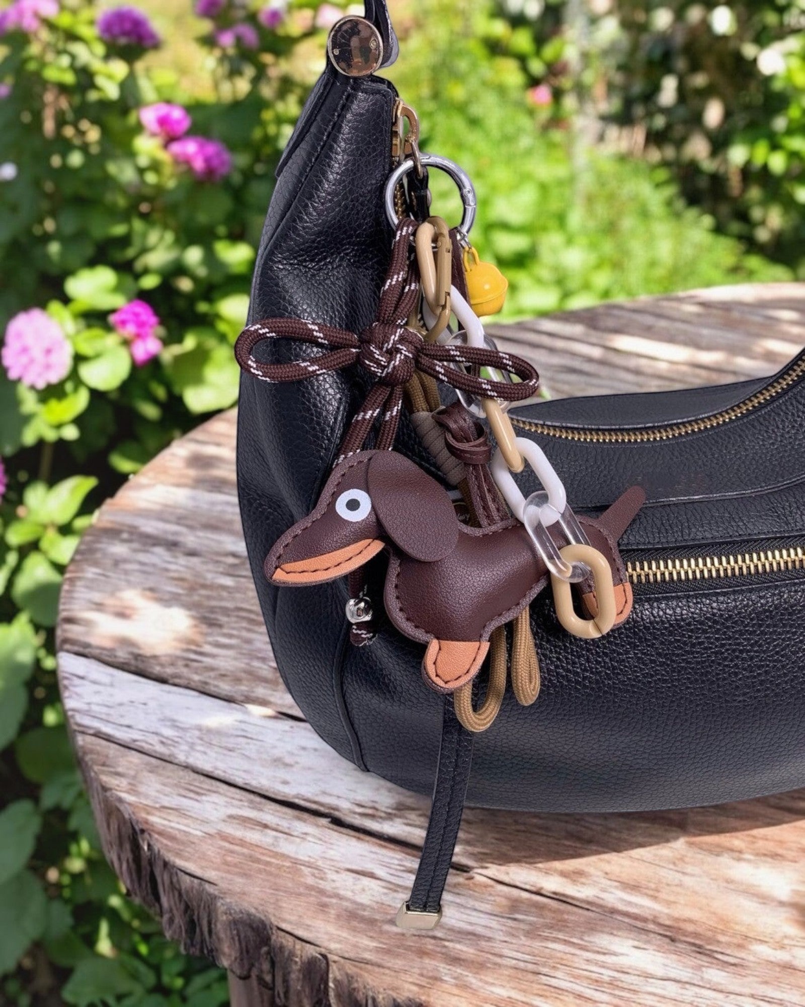 Porte-clés  en cuir marron en forme de chien teckel avec breloques colorées et clochette jaune.