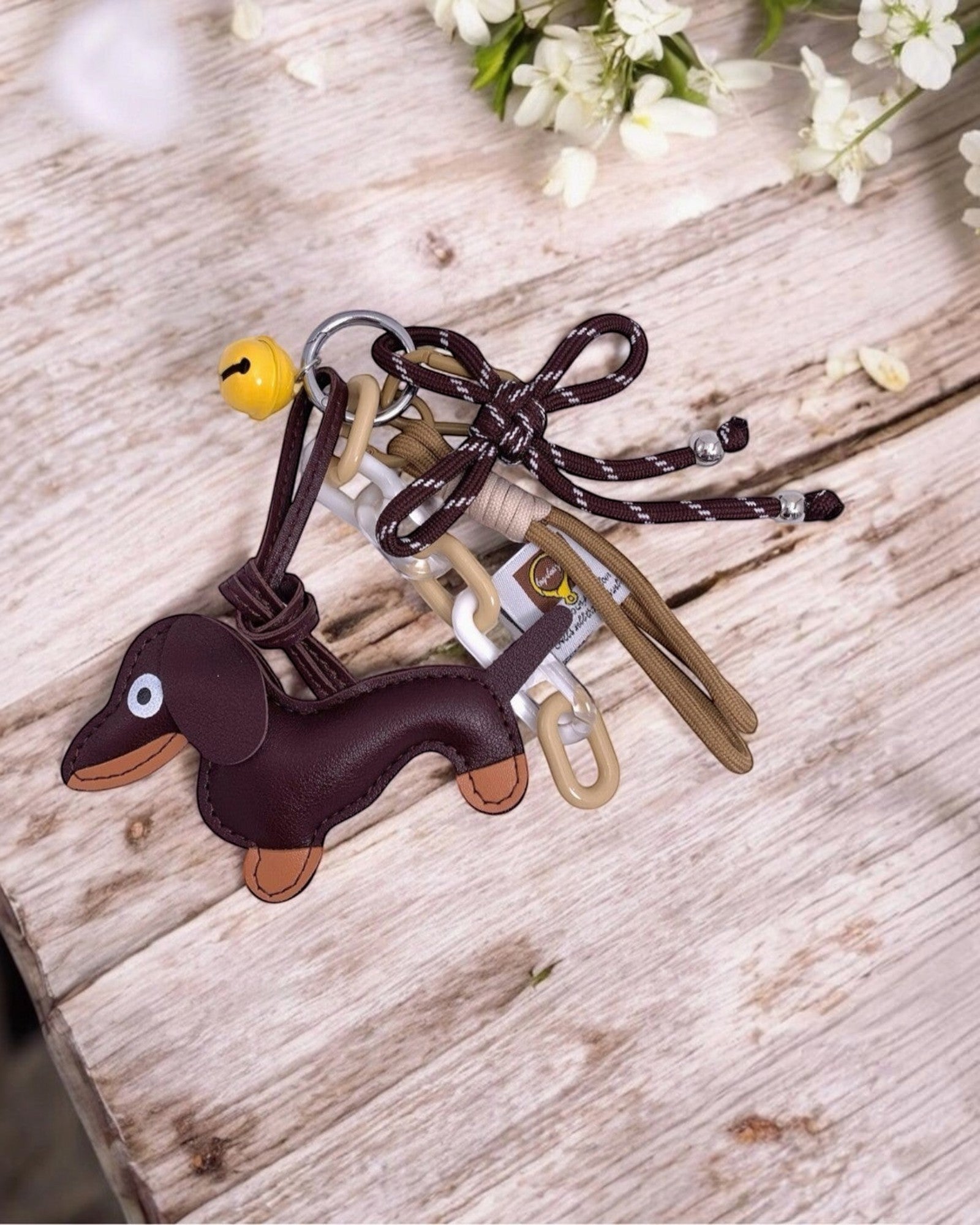Porte-clés en cuir marron en forme de chien teckel avec breloques clochette, chaînes et nœud.